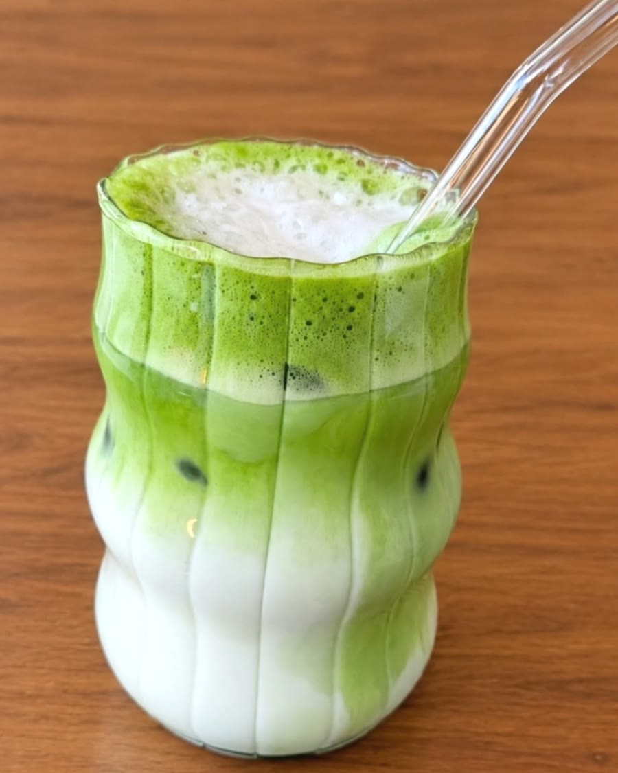 Iced matcha latte in a ribbed glass with a glass straw